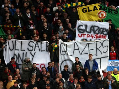 مشجعون لمانشستر يونايتد يحملون لافتات تطالب برحيل عائلة غليزر خلال المباراة ضد إشبيلية على ملعب أولد ترافورد - 13 أبريل 2023 - AFP