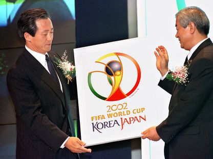 نائب رئيس الفيفا تشونغ مونغ جون (يسار) يسلّم شعار مونديال 2002 لتشوي تشانغ شين، سكرتير اللجنة الكورية المنظمة للحدث - AFP
