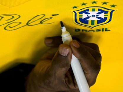 الأسطورة الراحل بيليه يوقع على قميص منتخب البرازيل - 10 يونيو 2013 - AFP