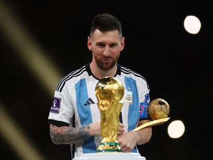 الأرجنتيني ليونيل ميسي ينظر إلى كأس العالم بعد نيله جائزة الكرة الذهبية - 18 ديسمبر 2022 - Reuters 