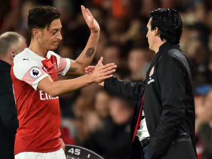 لاعب الوسط في أرسنال الألماني مسعود أوزيل يصافح المدرب السابق الإسباني أوناي إيمري - AFP