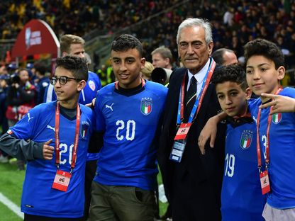 رئيس الاتحاد الإيطالي لكرة القدم، غابرييل غرافينا، برفقة أطفال في ملعب لكرة القدم - AFP