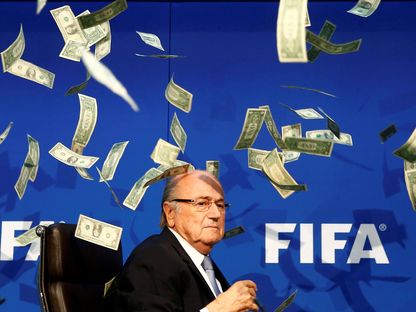 معارض لسياسات جوزيف بلاتر رئيس الاتحاد الدولي لكرة القدم السابق يلقي عليه حفنة من الأموال خلال مؤتمر صحافي. 20 يوليو 2015 - REUTERS