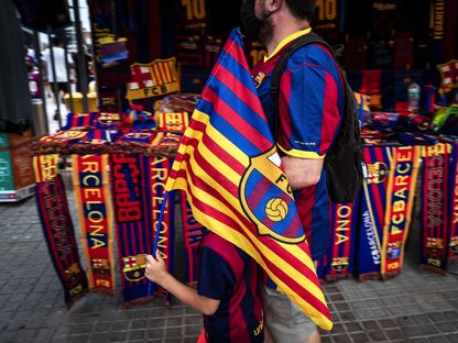 مشجع لبرشلونة وابنه يمرّان أمام متجر في ملعب "كامب نو" - 15 أغسطس 2021 - Bloomberg