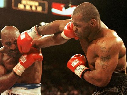 ايفاندر هوليفيلد (يسار) و مايك تايسون (يمين) يتنافسان في قتالهما في لاس فيغاس، نيفادا - AFP