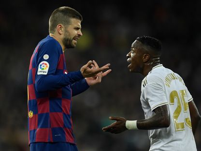 مدافع برشلونة الإسباني جيرارد بيكيه يتحدث مع مهاجم ريال مدريد البرازيلي فينيسيوس جونيور خلال مباراة الدوري الإسباني لكرة القدم على سانتياغو برنابيو في مدريد - AFP