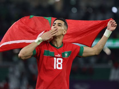 جواد الياميق يحتفل حاملاً العلم المغربي بعد التأهل لربع نهائي كأس العالم - 6 ديسمبر 2022 - REUTERS