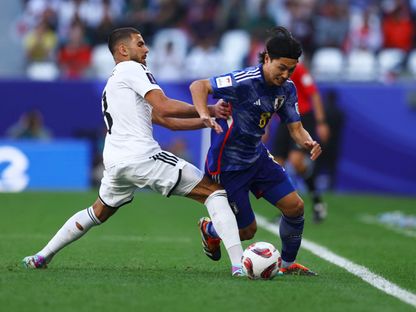 الياباني تاكومي مينامينو يتنافس على الكرة مع العراقي حسين علي خلال مباراة المنتخبين في كأس آسيا - 19 يناير 2024 - Reuters