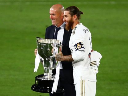 زين الدين زيدان مدرب ريال مدريد السابق وسيرخيو راموس قائد الفريق سابقاً يحملان كأس الدوري الإسباني - 16 يوليو 2020 - REUTERS
