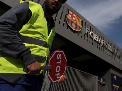 عامل بناء يحمل لافتة عند مدخل ملعب "كامب نو" في برشلونة - 1 يونيو 2023 - Reuters