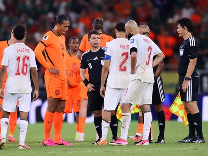 فيرجيل فان دايك وأشرف حكيمي رفقة حكم مباراة المغرب وهولندا في كأس العالم خلال إجراء القرعة قبل تنفيذ ركلات الترجيح - 30 يونيو 2026 - REUTERS