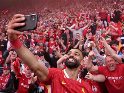 محمد صلاح يلتقط صورة سيلفي مع مشجعين لليفربول في "أنفيلد" بعد فوزه بلقب الدوري الإنجليزي الممتاز إثر مباراة ضد توتنهام هوتسبير - 27 أبريل 2025 - REUTERS