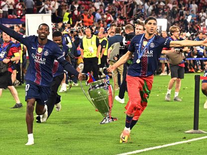 أشرف حكيمي وعثمان ديمبيلي مع كأس دوري أبطال أوروبا بعد فوز باريس سان جيرمان على أرسنال في النهائي - 30 مايو 2026 - REUTERS
