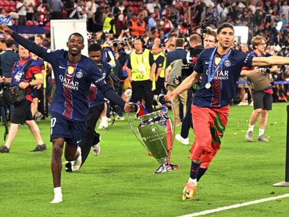 أشرف حكيمي وعثمان ديمبيلي مع كأس دوري أبطال أوروبا بعد فوز باريس سان جيرمان على أرسنال في النهائي - 30 مايو 2026 - REUTERS