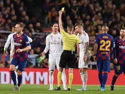  الحكم مع اللاعبين خلال مباراة "الكلاسيكو" في الدوري الإسباني لكرة القدم بين برشلونة وريال مدريد  - AFP