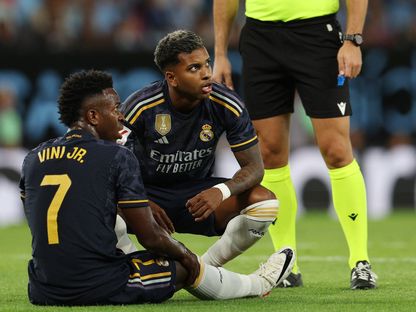 فينيسيوس جونيور مهاجم ريال مدريد يسقط أرضاً بعد إصابته أمام سيلتا فيغو وإلى جواره رودريغو - 25 أغسطس 2023 - reuters