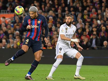 رونالد أراوخو مدافع برشلونة يضرب الكرة برأسه تحت أنظار كريم بنزيما قائد ريال مدريد في الكلاسيكو - 20 مارس 2023 - AFP