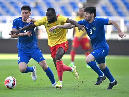 اللاعب الكاميروني نجامولو بين لاعبين اثنين من المنتخب الأوزبكستاني. 23 سبتمبر 2022 - AFP