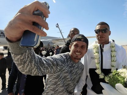 مشجع يلتقط صورة سيلفي مع كيليان مبابي لدى وصول باريس سان جيرمان إلى السعودية - 19 يناير 2023 - Reuters 