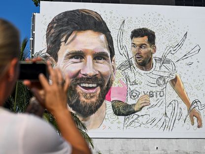 امرأة تلتقط صورة لجدارية أعدّها الفنان الأرجنتيني ماكسيميليانو باغناسكو للنجم ليونيل ميسي في ميامي - 10 يوليو 2023 - AFP