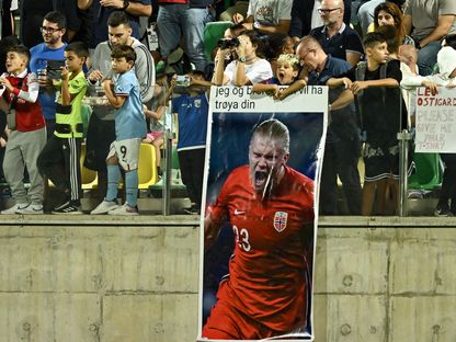 مشجعون يرفعون ملصقاً عليه صورة لإيرلينغ هالاند خلال مباراة بين قبرص والنرويج في تصفيات "يورو 2024" - 12 أكتوبر 2023 - AFP
