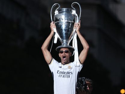 جود بيلينغهام يرفع كأس دوري أبطال أوروبا خلال احتفالات ريال مدريد في ساحة "سيبيليس" بالعاصمة الإسبانية - 2 يونيو 2024 - AFP