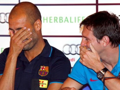 ليونيل ميسي وبيب غوارديولا يضحكان في مؤتمر صحفي لفريقهما السابق برشلونة خلال الجولة التحضيرية للموسم في بكين - 5 أغسطس 2010 - REUTERS