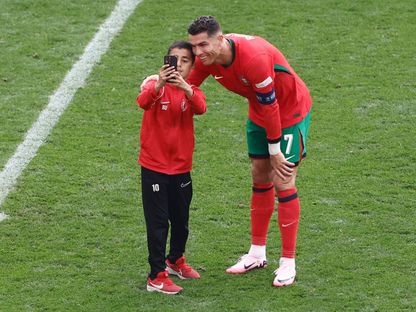 كريستيانو رونالدو يلتقط صورة مع فتى على الملعب خلال مباراة بين البرتغال وتركيا في "يورو 2024" - 22 يونيو 2024 - AFP