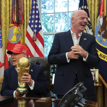 الرئيس الأميركي دونالد ترمب يحمل كأس العالم لكرة القدم وإلى يساره رئيس "فيفا" جياني إنفانتينو في المكتب البيضاوي بالبيت الأبيض - 22 أغسطس 2025