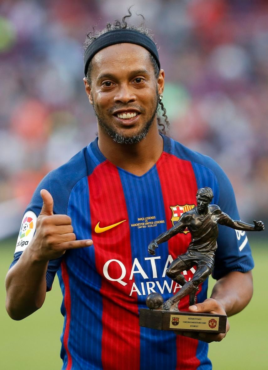 مهاجم برشلونة البرازيلي السابق رونالدينيو يحمل كأس أفضل لاعب بعد مباراة كرة قدم خيرية  - AFP