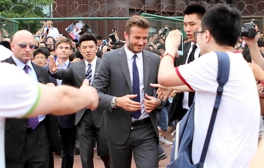 مرافقة نجم كرة القدم ديفيد بيكهام (وسط) من قبل أفراد الأمن في جامعة تونجي في شنغهاي في 20 يونيو 2013, AFP