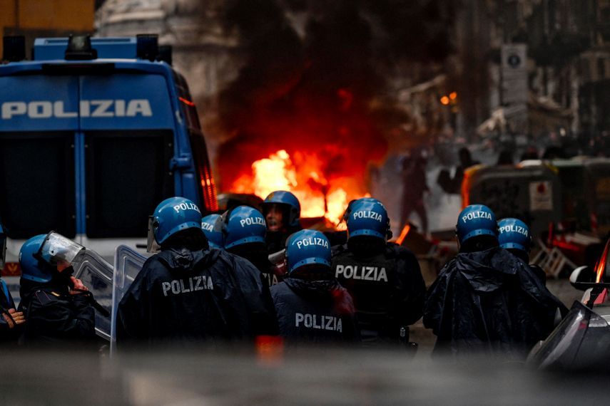 عناصر شرطة نابولي في حالة تأهب وأمامهم سيارة مشتعلة بعد الاشتباك مع مشجعي نادي آينتراخت فرانكفورت - 15 مارس 2023