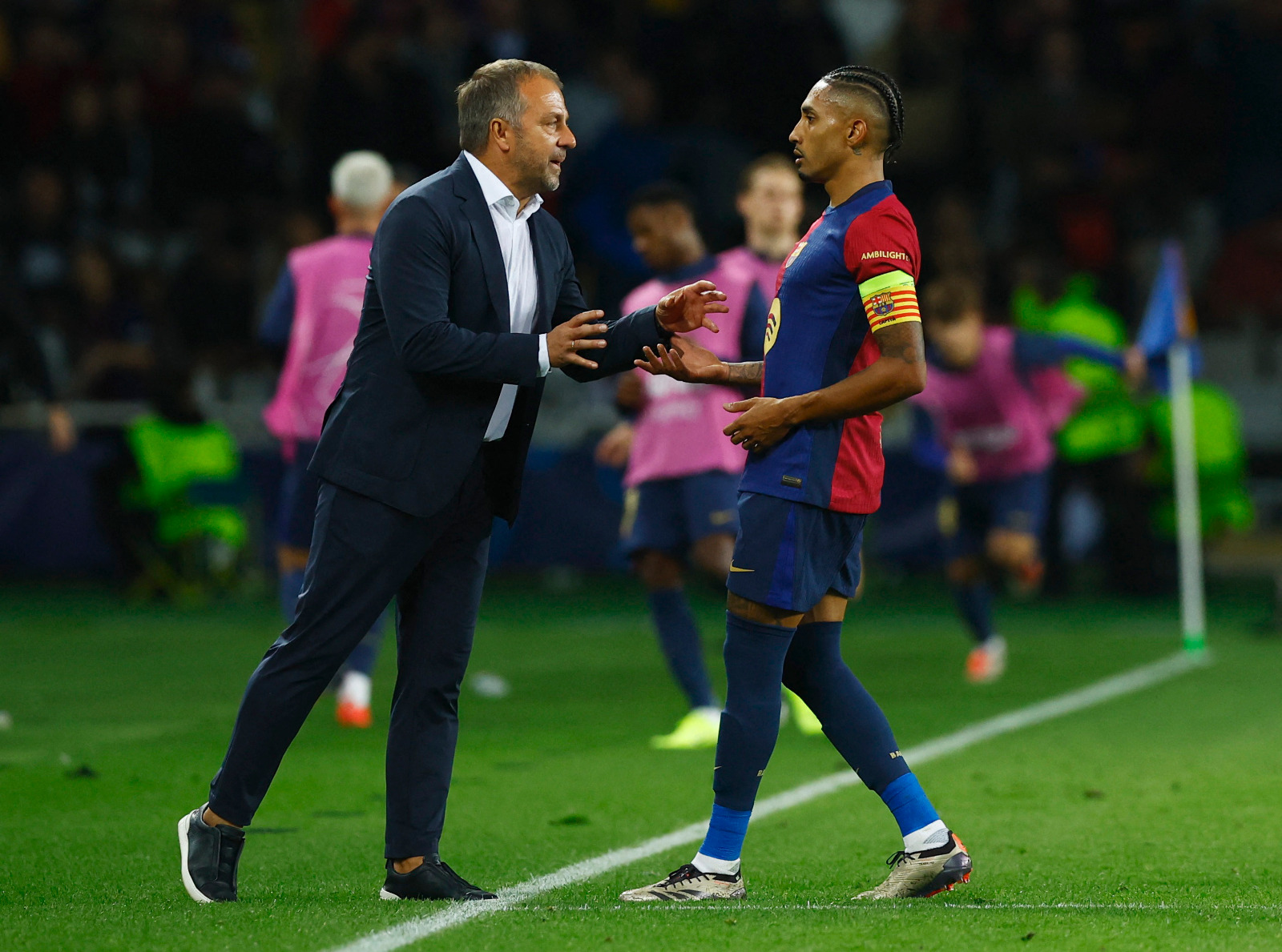 رافينيا يتحدث إلى مدرب برشلونة هانزي فليك خلال مباراة ضد بايرن ميونيخ في دوري أبطال أوروبا - 23 أكتوبر 2024