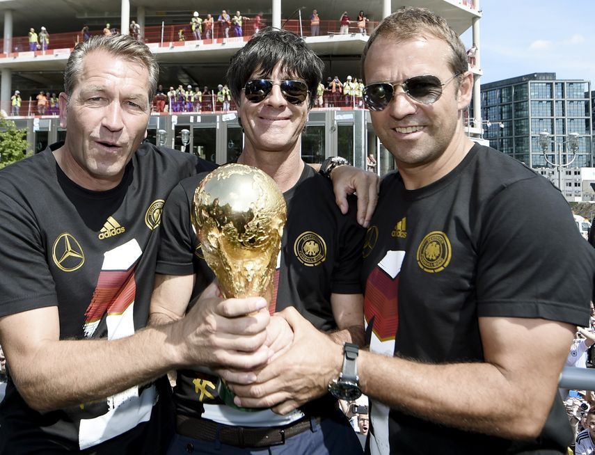 المدرب السابق لمنتخب ألمانيا يواخيم لوف (وسط) وهانزي فليك (يمين) ومدرب الحراس أندرياس كوبكي يحملون كأس العالم - 15 يوليو 2014