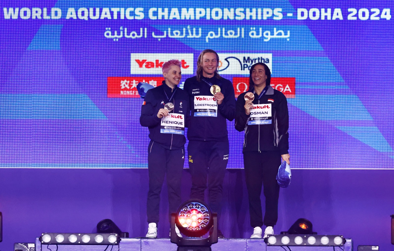 المصرية فريدة عثمان (أقصى اليمين) بعد تتويجها ببرونزية بطولة العالم للسباحة بالدوحة في منافسات 50 متراً فراشة - 17 فبراير 2024