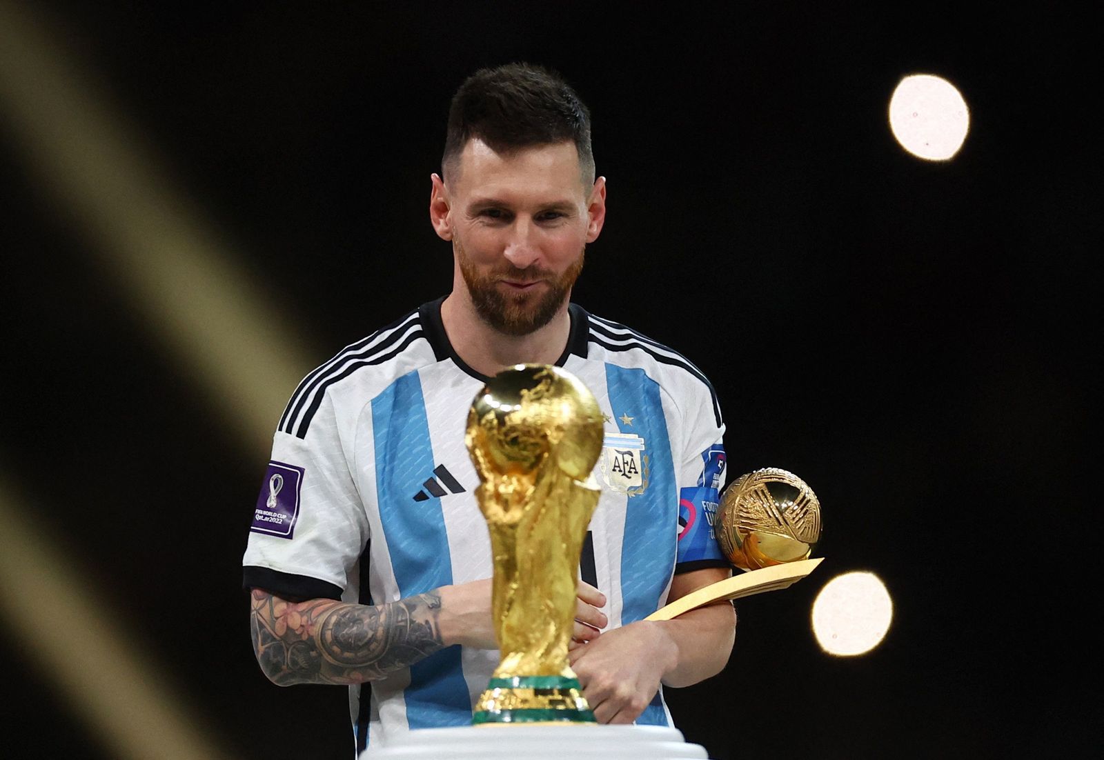 الأرجنتيني ليونيل ميسي ينظر إلى كأس العالم بعد نيله جائزة الكرة الذهبية - 18 ديسمبر 2022